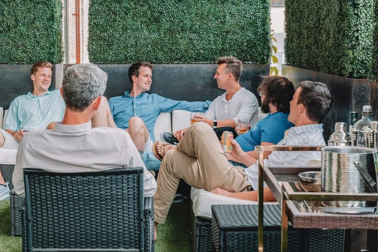 Männerrunde beim entspannten Gespräch in einem eleganten Außenbereich.